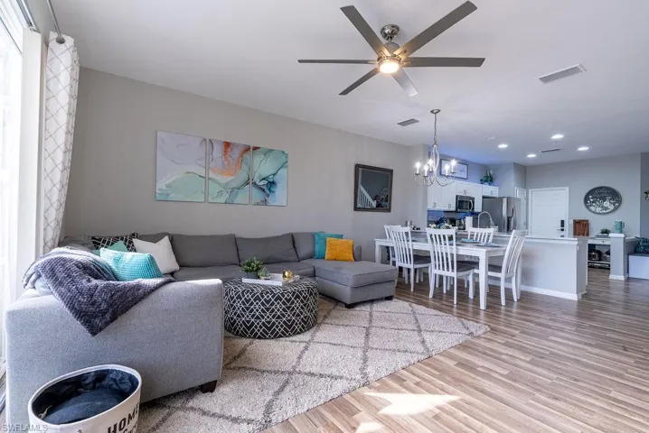 Living room featuring light wood-style floors, a ceiling fan, and a chandelier