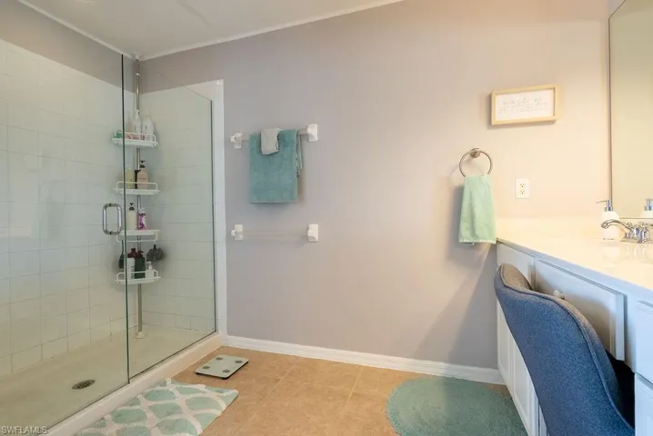 Full bath with vanity, a stall shower, ornamental molding, and light tile patterned floors