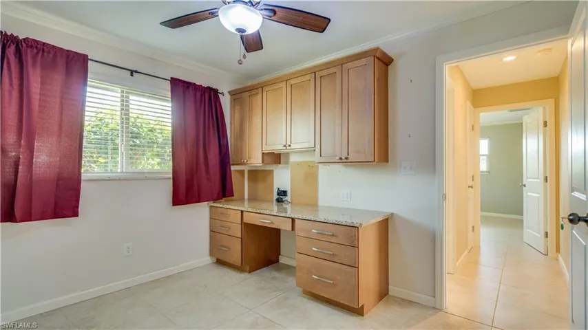 Tiled home office featuring crown molding, built in desk, and ceiling fan