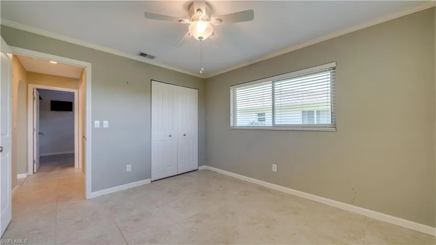 Bedroom with ceiling fan, tile floors and crown molding