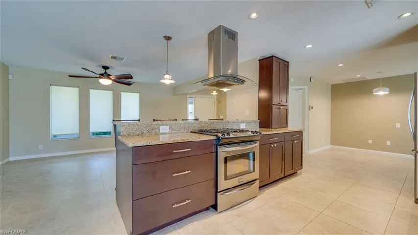 Kitchen with gas stove, granite countertops, light tile floors  and pendant lighting