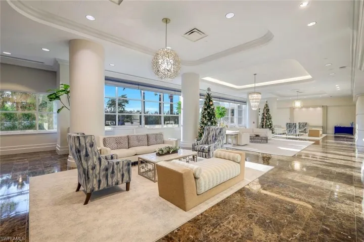 Living room with a chandelier, a raised ceiling, and ornamental molding