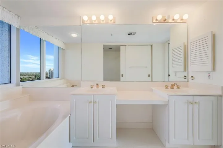 Bathroom with tile patterned floors, vanity, and a tub to relax in