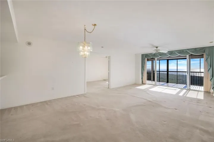 Empty room featuring light carpet and ceiling fan with notable chandelier