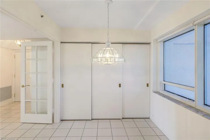 Unfurnished dining area with light tile patterned floors and a notable chandelier