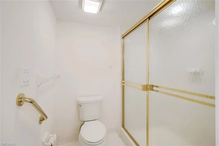 Bathroom featuring tile patterned flooring, toilet, and a shower with shower door