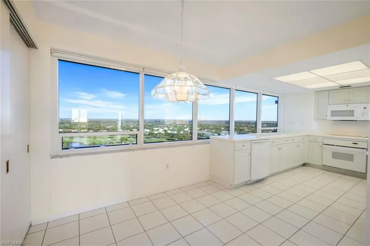 Kitchen with plenty of natural light, white cabinets, pendant lighting, and white appliances