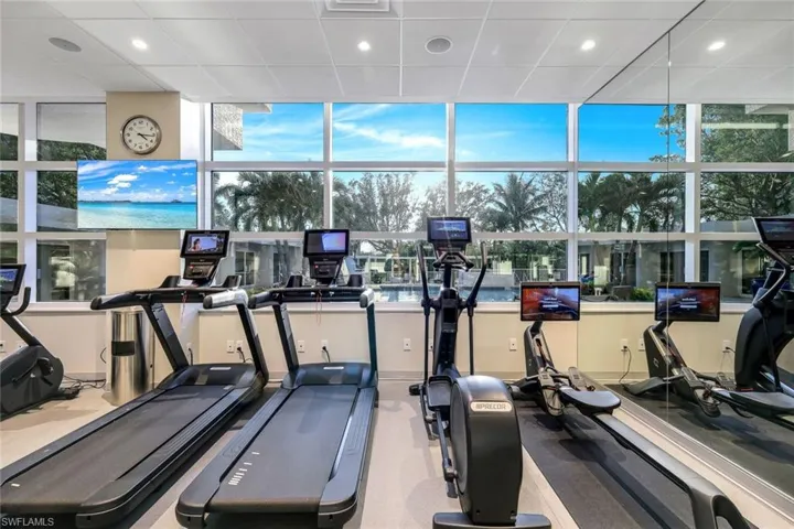 Gym featuring a drop ceiling, a wall of windows, and plenty of natural light
