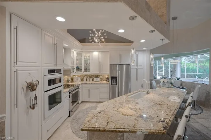 Kitchen with appliances with stainless steel finishes, white cabinetry, sink, hanging light fixtures, and a raised ceiling
