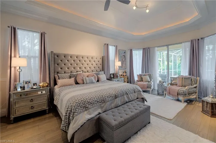 Bedroom with crown molding, access to exterior, a tray ceiling, and light hardwood / wood-style floors