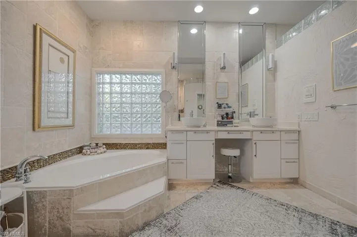 Bathroom with vanity and tiled bath