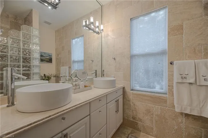 Bathroom with vanity, tile walls, and a notable chandelier