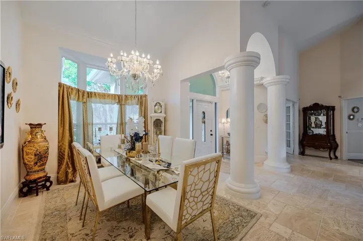 Dining area with ornate columns, a notable chandelier, and high vaulted ceiling
