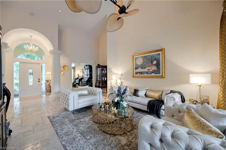Living room with decorative columns, a towering ceiling, and an inviting chandelier