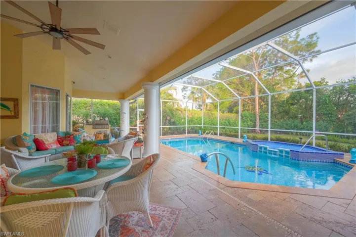 View of pool ceiling fan, glass enclosure, and a patio area