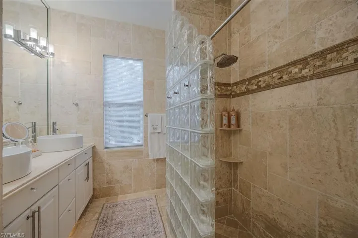 Bathroom featuring vanity, tile walls, and a tile shower