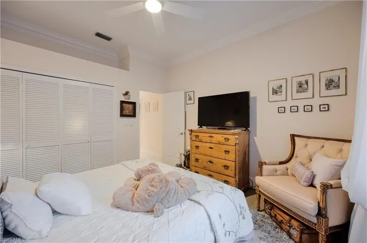Bedroom with ornamental molding, ceiling fan, and a closet