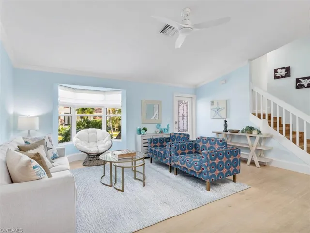 Living room featuring stairway, wood finished floors, crown molding, and a ceiling fan