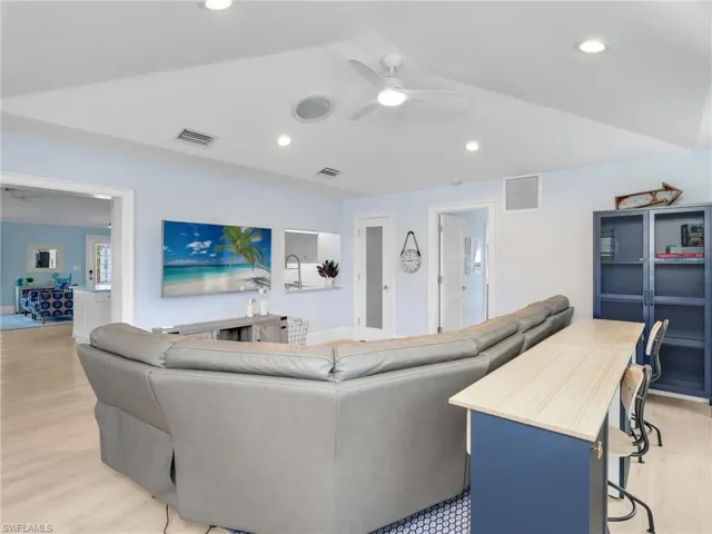 Living room with ceiling fan, light wood-style floors, recessed lighting, and lofted ceiling