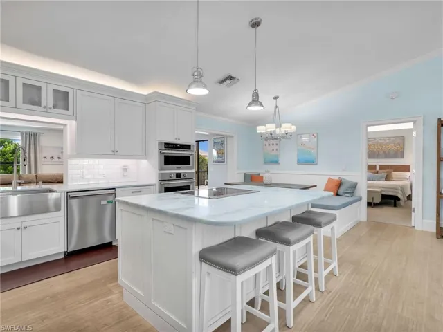 Kitchen with lofted ceiling, a breakfast bar, white cabinets, ornamental molding, and a kitchen island