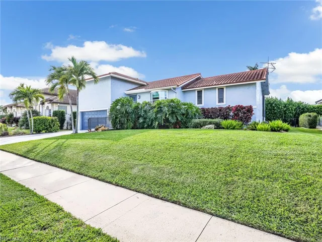 Mediterranean / spanish house featuring a front yard, a tiled roof, stucco siding, an attached garage, and driveway