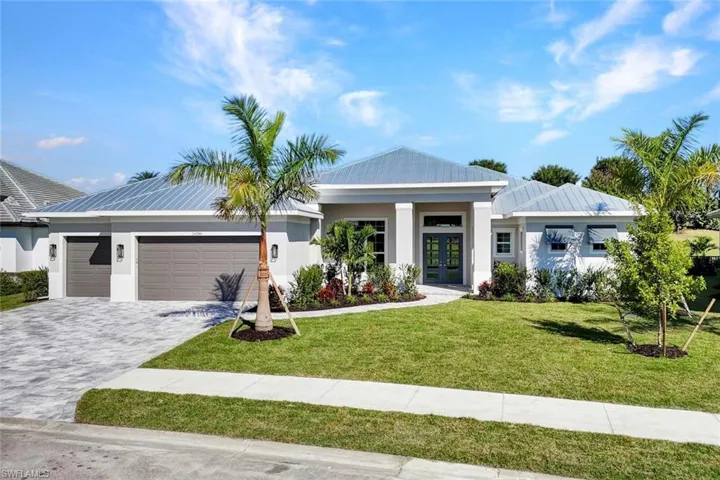 View of front facade with a front yard, decorative driveway, stucco siding, a garage, and french doors