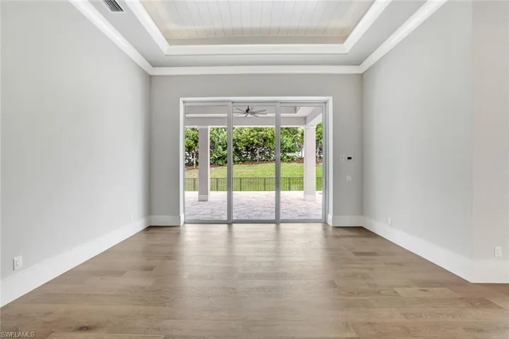 Spare room featuring crown molding, wood finished floors, and a raised ceiling