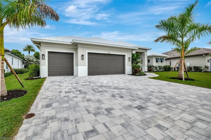View of front of home with a front lawn, an attached garage, stucco siding, and decorative driveway