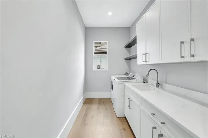 Laundry area with light wood finished floors, cabinet space, separate washer and dryer, and recessed lighting
