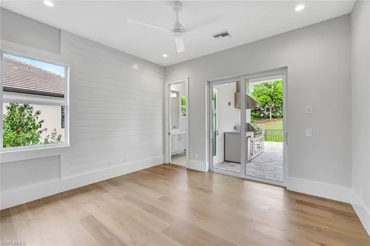 Empty room featuring light wood-type flooring, wooden walls, a ceiling fan, and recessed lighting