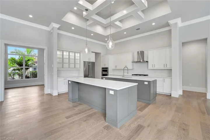 Kitchen with gray cabinets, white cabinets, a towering ceiling, coffered ceiling, and hanging light fixtures