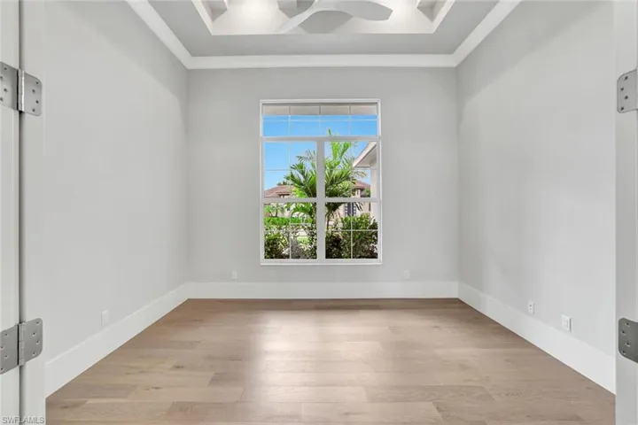 Empty room with crown molding, light wood finished floors, and a ceiling fan