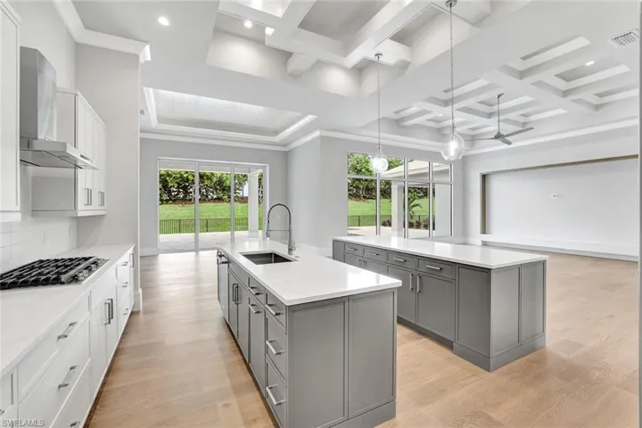 Kitchen with decorative light fixtures, gray cabinets, open floor plan, white cabinets, and coffered ceiling