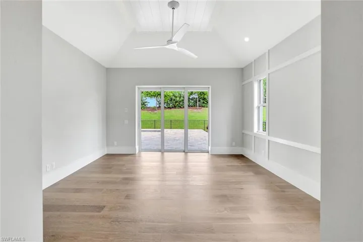 Spare room featuring wood finished floors, ceiling fan, and lofted ceiling