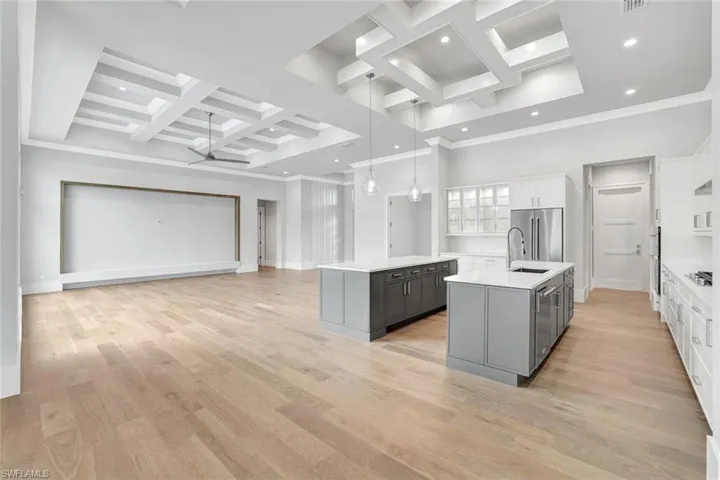 Kitchen featuring coffered ceiling, gray cabinetry, hanging light fixtures, white cabinets, and light wood-style floors
