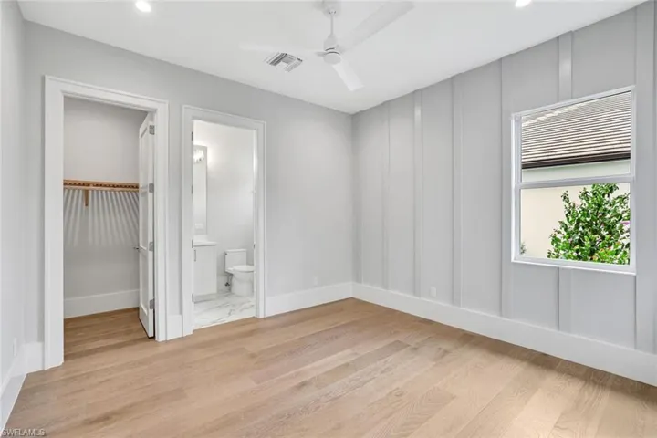 Unfurnished bedroom featuring a spacious closet, light wood-type flooring, ceiling fan, recessed lighting, and a decorative wall