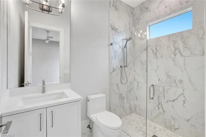 Bathroom with vanity, a marble finish shower, a chandelier, and marble finish flooring