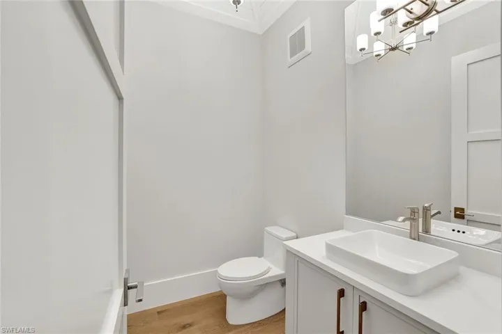 Half bath featuring vanity, light wood-style floors, and a chandelier