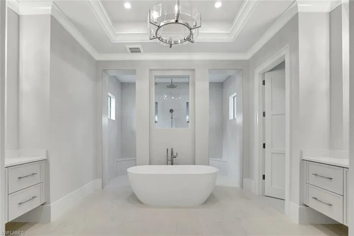 Full bathroom featuring a walk in shower, vanity, a freestanding tub, healthy amount of natural light, and ornamental molding