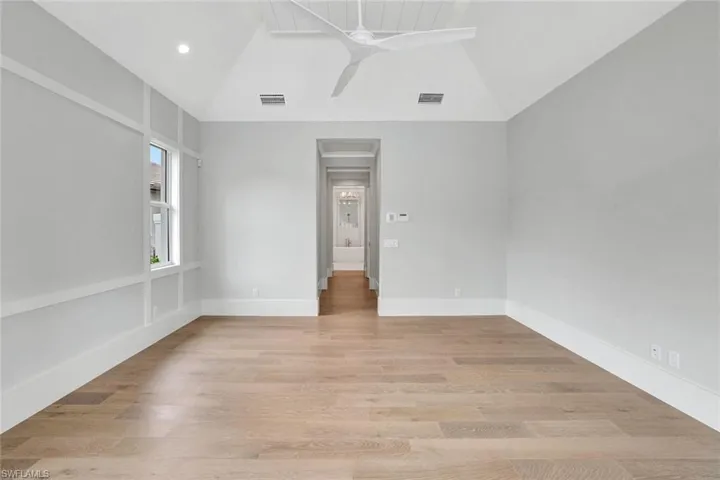 Unfurnished room featuring a ceiling fan, lofted ceiling, and light wood-type flooring