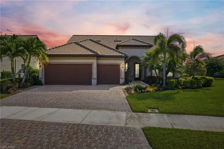 Mediterranean / spanish house with a yard, stucco siding, decorative driveway, an attached garage, and a tiled roof