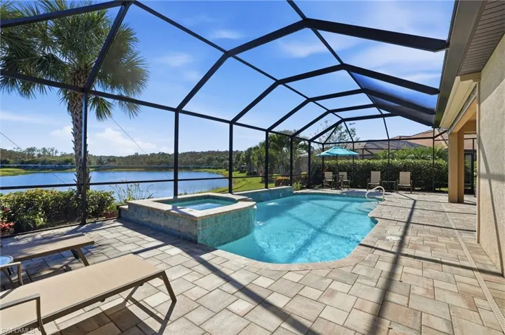View of swimming pool with a sunroom, glass enclosure, a patio, a pool with connected hot tub, and a water view