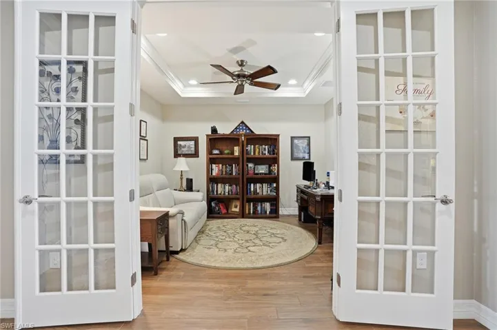 Living area with a desk, wood finished floors, ceiling fan, recessed lighting, and a raised ceiling