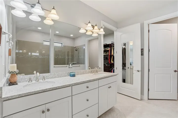 Bathroom featuring a spacious closet, a stall shower, double vanity, light tile patterned floors, and recessed lighting