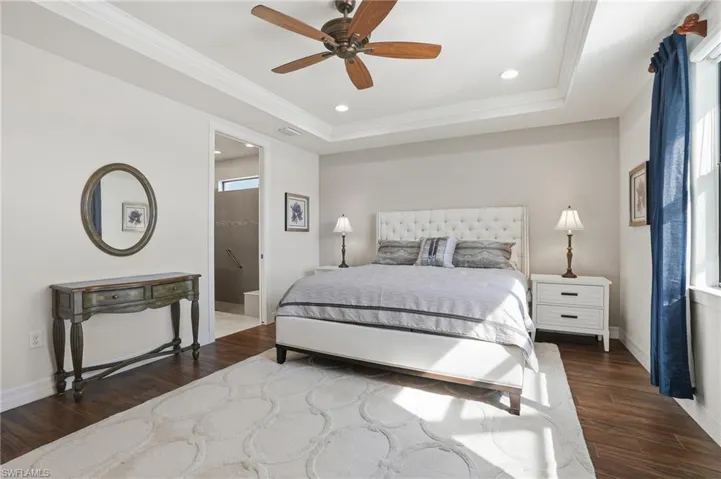 Bedroom featuring a raised ceiling, dark wood-style floors, crown molding, ceiling fan, and recessed lighting