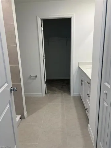 Bathroom featuring vanity, a walk in closet, and light tile patterned floors