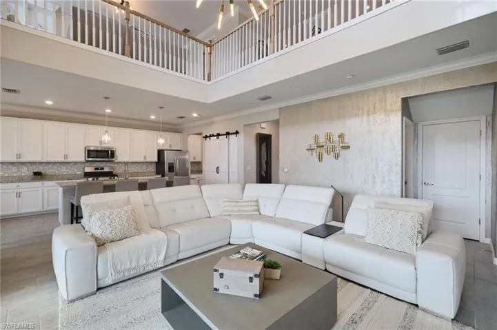 Living room with a towering ceiling, sink, ornamental molding, and a barn door