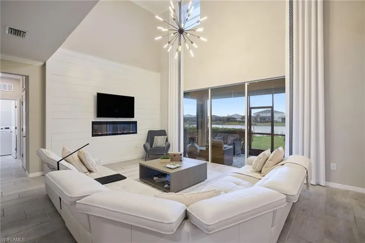 Living room with washer / clothes dryer, an inviting chandelier, and ornamental molding