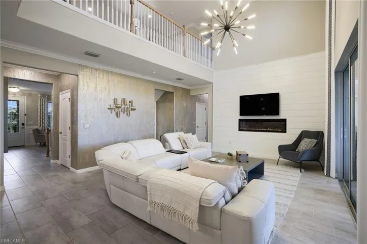 Living room with crown molding, a chandelier, and a high ceiling