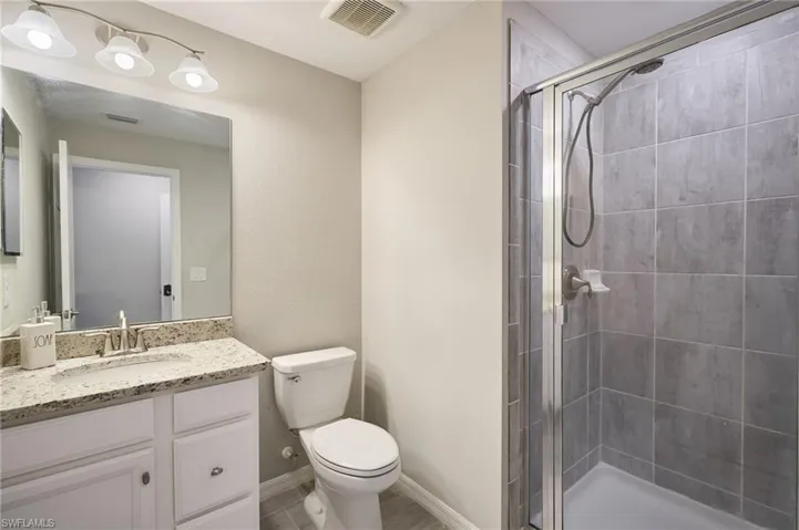 Bathroom featuring toilet, a shower with door, and vanity
